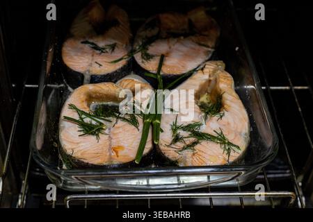 Salmon steaks baked in the oven. Salmon walls with herbs on a glass baking sheet. In the oven. Stock Photo