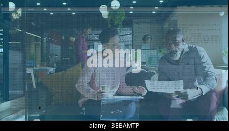 Discussing four coworkers in business-casual reviewing laptop and papers in lounge, code overlay Stock Photo