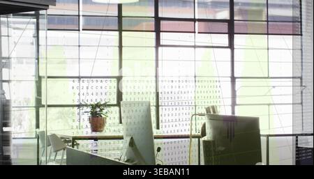 Displaying floor-to-ceiling grid glass windows projecting code overlay in open office, with desks Stock Photo