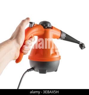 A hand holds the ergonomic handle of an orange and grey portable steam cleaner machine Stock Photo
