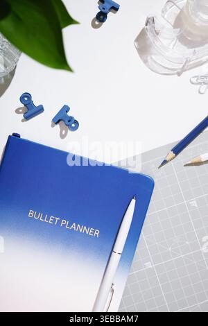 Closed blue notebook with pen, pencils, and clips on a white background. Stationery background. copyspace Stock Photo