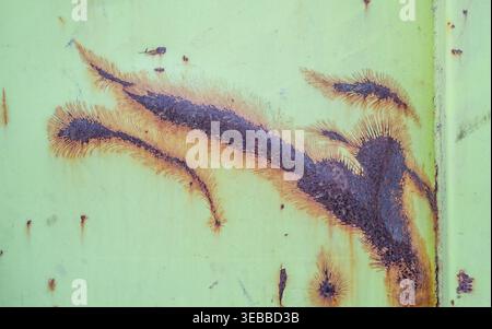 Rust and corrosion are spreading on a green painted metal surface of an industrial structure Stock Photo