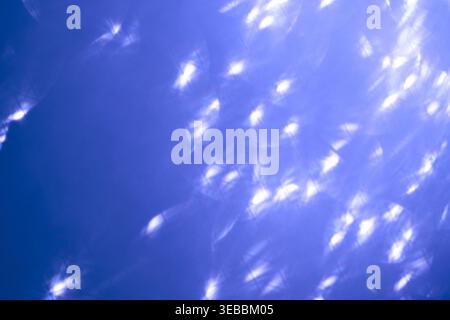 Bright Light Reflections Scattering Across Blue Background Creating Sparkling Aquatic Effect With Numerous Bright Highlights Soft Flares And Translucent Shimmer Suggesting Water Surface Motion. Stock Photo
