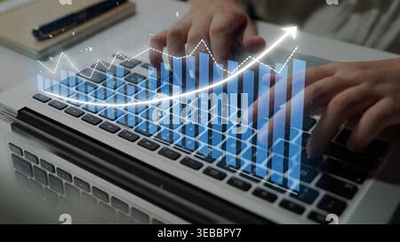 A close-up image of hands typing on a laptop keyboard, overlaid with upward trending graphs and data visualizations, representing business growth and Stock Photo