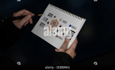 Close-up of hands holding an open sketchbook filled with various symbols and drawings, showcasing the process of creativity and artistic exploration Stock Photo