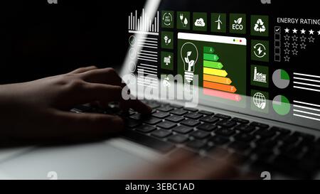 Close-up of a hand on a laptop keyboard displaying an energy efficiency interface, showcasing charts and graphics for sustainability and green Stock Photo