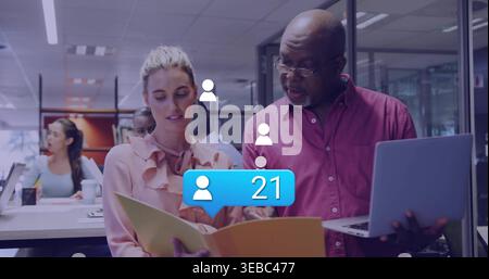 Checking yellow folder, woman in pink blouse, man magenta shirt talking in open office, alert 21 Stock Photo