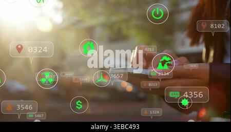 Holding Asian woman wearing dark jacket tapping smartphone on street, with AR icons, copy space Stock Photo