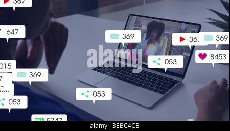 Displaying laptop showing host, team viewing clip on home desk with icons, right in dark-blue shirt Stock Photo