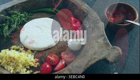 Displaying carved wooden tray with dough disc, tomatoes, garlic, chili, herbs, sauce cup on slate Stock Photo