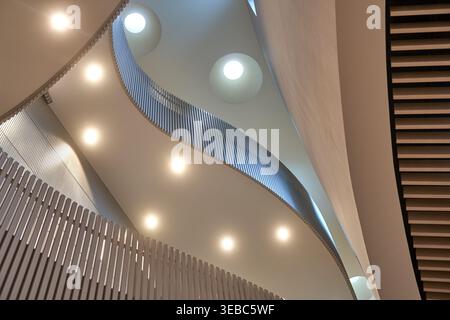 A low-angle view capturing the interior of a modern architectural space featuring sweeping curved ceilings and multiple levels. The composition Stock Photo