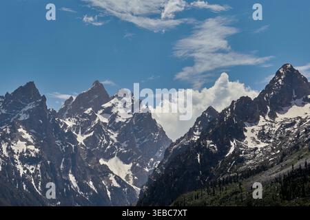 Dramatic close-up of the rugged granite peaks of the Grand Teton Range with snow fields and alpine shadows under a bright summer sky. Stock Photo