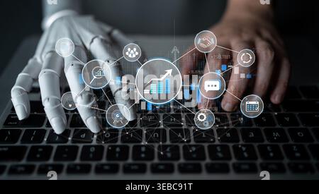 Human and robotic hands working together on a laptop, showcasing data analysis, technology integration, and the future of automation in business Stock Photo