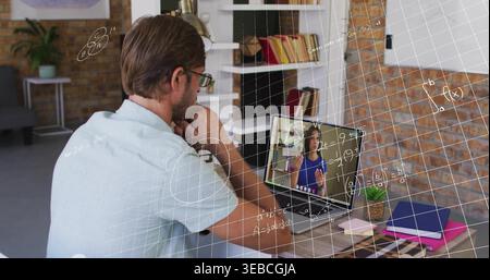 Watching mid-adult man wearing light polo listening to remote presenter on laptop at home office Stock Photo
