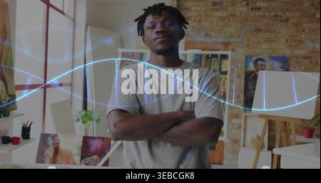 Standing dreadlocked man crossing arms, facing camera in studio in grey tee, blue helix projecting Stock Photo