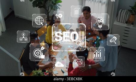 A diverse team collaborates in a modern office environment working on SEO strategy. Digital icons illustrate concepts like analytics, communication Stock Photo