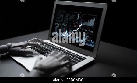 A robotic hand interacts with a laptop displaying dynamic data graphs, reflecting innovations in technology and the future of automation in a dark Stock Photo