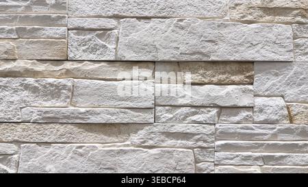 Close-up of white decorative stone wall texture with layered masonry pattern and rough surface Stock Photo