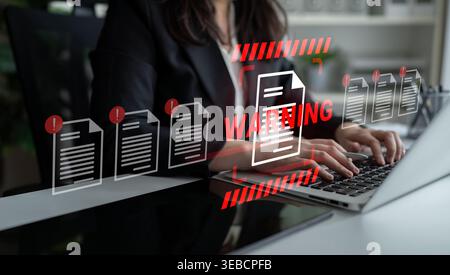 A business professional types on a laptop, featuring a warning overlay about document issues. This scene highlights the importance of cybersecurity in Stock Photo