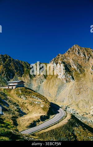 Isolated alpine house, mountain cabin beneath dramatic rocky peaks in Fagaras Mountains. Transfagarasan Highway, Romania. Stock Photo