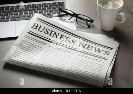 Newspaper, laptop, glasses and coffee on grey table, closeup Stock Photo