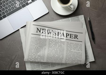 Newspapers, laptop, pen and coffee on grey textured table, flat lay Stock Photo