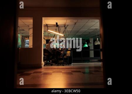 Diverse team of thieves coding trojan virus late at night, hacking computer system with malware. Young hackers planning to crack server, looking to steal passwords, malicious software. Stock Photo