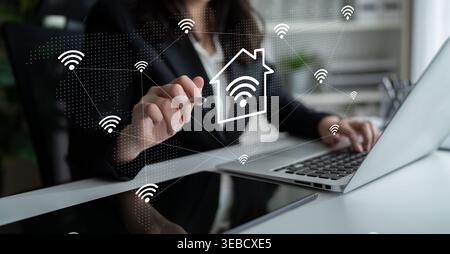 A business professional interacts with a laptop displaying smart home network icons, emphasizing the importance of connectivity and digital solutions Stock Photo