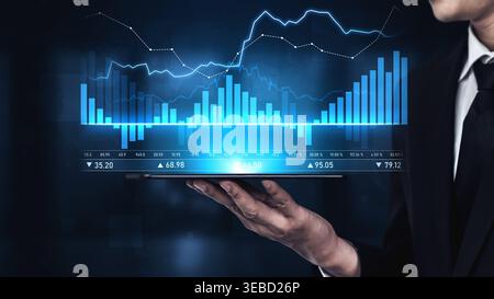A business professional evaluates financial data using a digital tablet, showcasing glowing graphs and charts that reflect market trends and stock Stock Photo