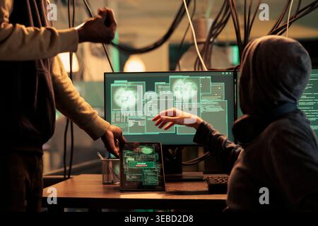 Angry hackers failing to hack computer system online, using monitors and tablet late at night. Unsuccessful password cracking, trying to access server for cyberattack, stealing data. Stock Photo