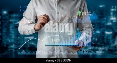 Business professional examines financial data on a tablet while digital graphs and charts display market trends and investment insights against a Stock Photo