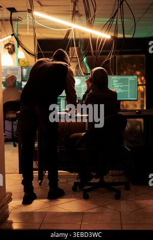 Team of spies using trojan virus to crack encryption and steal government information from database. Committing cyberattack and cybercrime with malware, access program late at night. Stock Photo