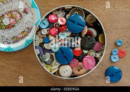 Vintage buttons in old round Quality Street tin box on wooden tray Stock Photo