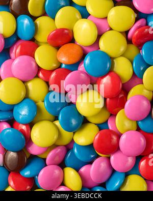 multi colored candy coated chocolate buttons, vibrant round sweets in red yellow blue pink and orange, top view closeup, dessert background Stock Photo
