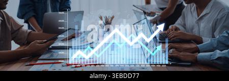 A dynamic office scene showcasing a diverse team collaborating over digital devices, with an analytics graph illustrating trends and growth for Stock Photo