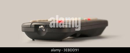 black plastic remote control with infrared transmitter bulb on grey background, wireless technology and signal transmission, side view with soft focus Stock Photo