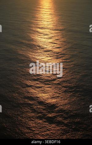 Aerial view of golden sunlight reflecting on the rippled surface of the Atlantic Ocean during sunset Madeira, Portugal. Stock Photo
