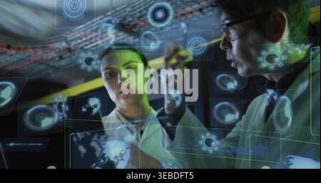 Studying two researchers in white lab coats manipulating holographic displays in lab operations bay Stock Photo