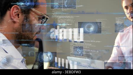 Reviewing man wearing glasses, button shirt leaning over laptop at office, HUD overlays, copy space Stock Photo