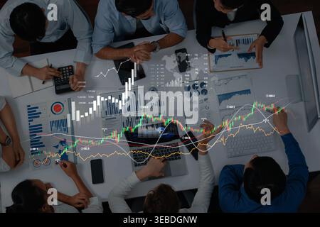 A diverse group of professionals collaborates in an office environment, analyzing financial data and discussing strategy while reviewing dynamic Stock Photo