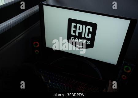 The Epic Games logo is displayed on a computer monitor in a dimly lit home office setting Stock Photo