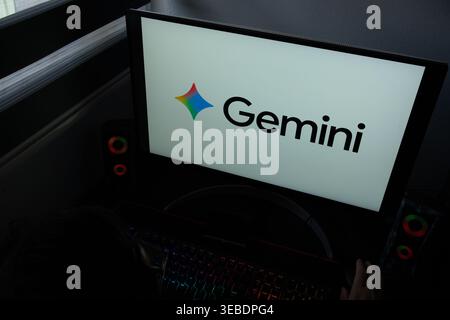 The Google Gemini AI logo and star icon are displayed on a computer monitor in a dark home office setting Stock Photo