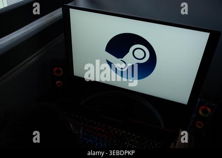 The Steam video game digital distribution platform logo is displayed on a computer monitor in a dark room Stock Photo