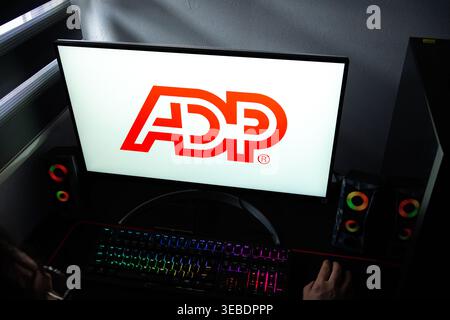 A person at a desk with the ADP corporate logo displayed on a computer monitor Stock Photo