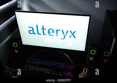 A person at a desk with the Alteryx data analytics logo displayed on a computer monitor Stock Photo