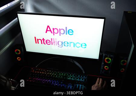 A person at a desk with the Apple Intelligence logo displayed on a computer monitor Stock Photo