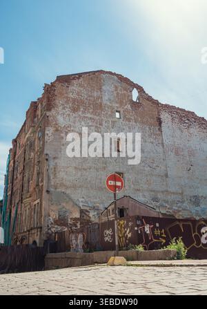 Vyborg, Russia - June 27, 2021: Weathered urban facade of a large old building with exposed bricks and plaster, featuring a street sign Stock Photo
