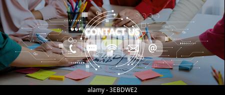 A diverse group works together at a table covered with colorful sticky notes and digital icons to symbolize modern communication and collaboration Stock Photo