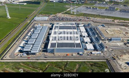 Aerial view of Datacenter Westpoort featuring extensive solar panels on the roof and cooling systems surrounded by green fields in Groningen, Groninge Stock Photo
