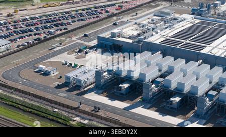 Aerial view of Datacenter Westpoort featuring industrial cooling units, modern facility buildings, and a large parking lot under bright daylight in Gr Stock Photo